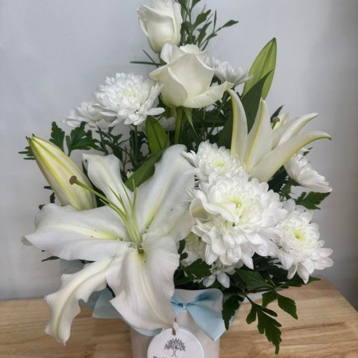 Seasonal white flower arrangement with fresh foliage and ceramic quote from My Florist Launceston