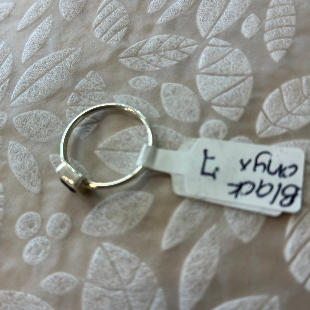 Black Onyx size 7 Sterling Silver ring with a label on a textured beige background