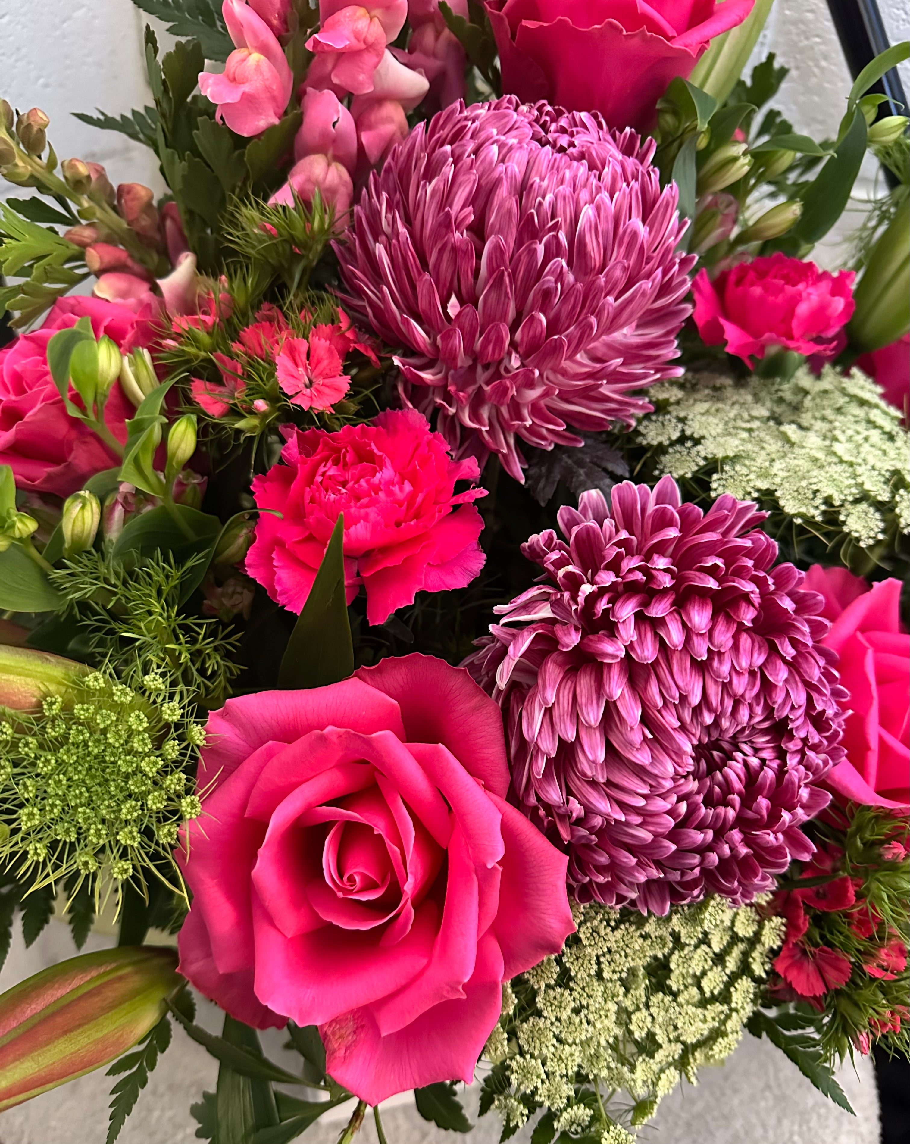 A close-up of a vibrant flower bouquet featuring bright pink roses, magenta chrysanthemums, pink carnations. Florist Riverside Tasmania