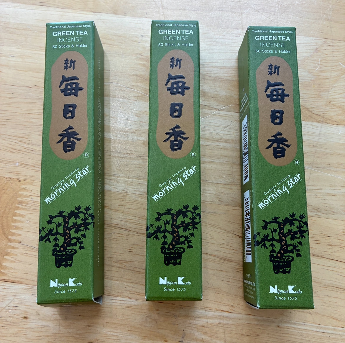 Three green boxes of Morning Star Green Tea Incense placed side by side on a light wood surface.