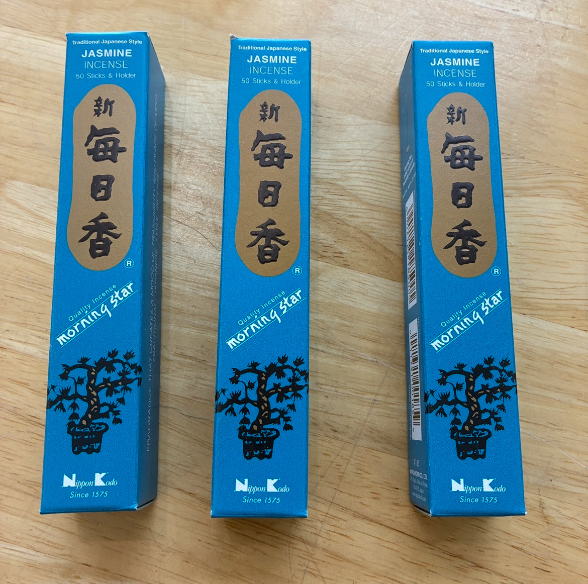 Three blue boxes of Morning Star Jasmine Incense sticks arranged side-by-side on a light-colored wooden surface.