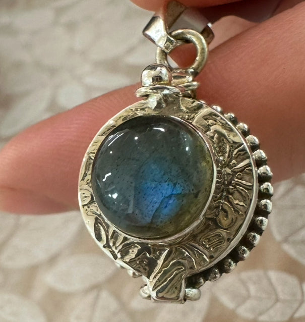 Labradorite Locket Sterling Silver pendant held by a hand on a textured surface at My Florist Launceston