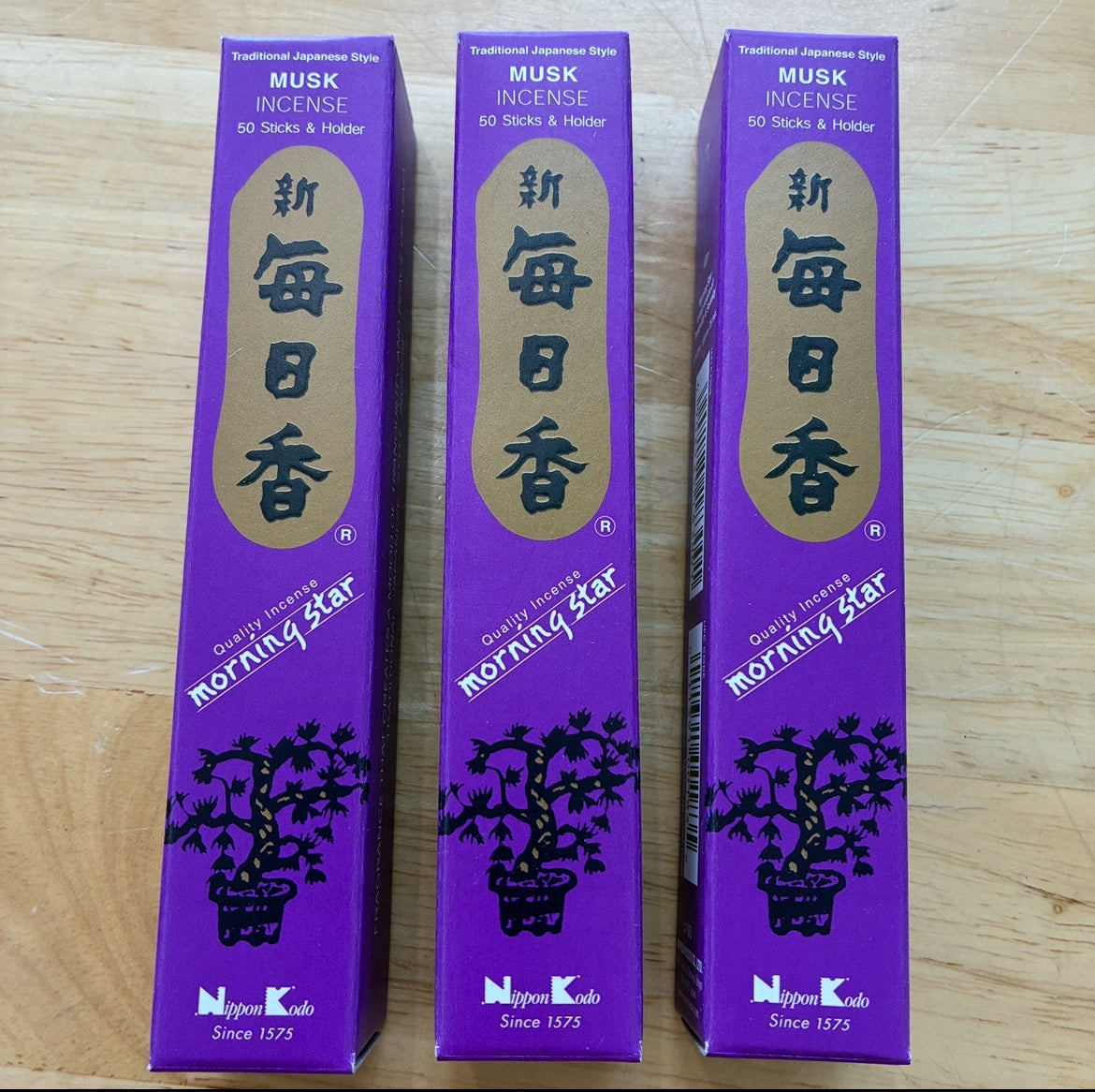 Three purple boxes of Morning Star Musk Incense standing upright on a light wood surface.