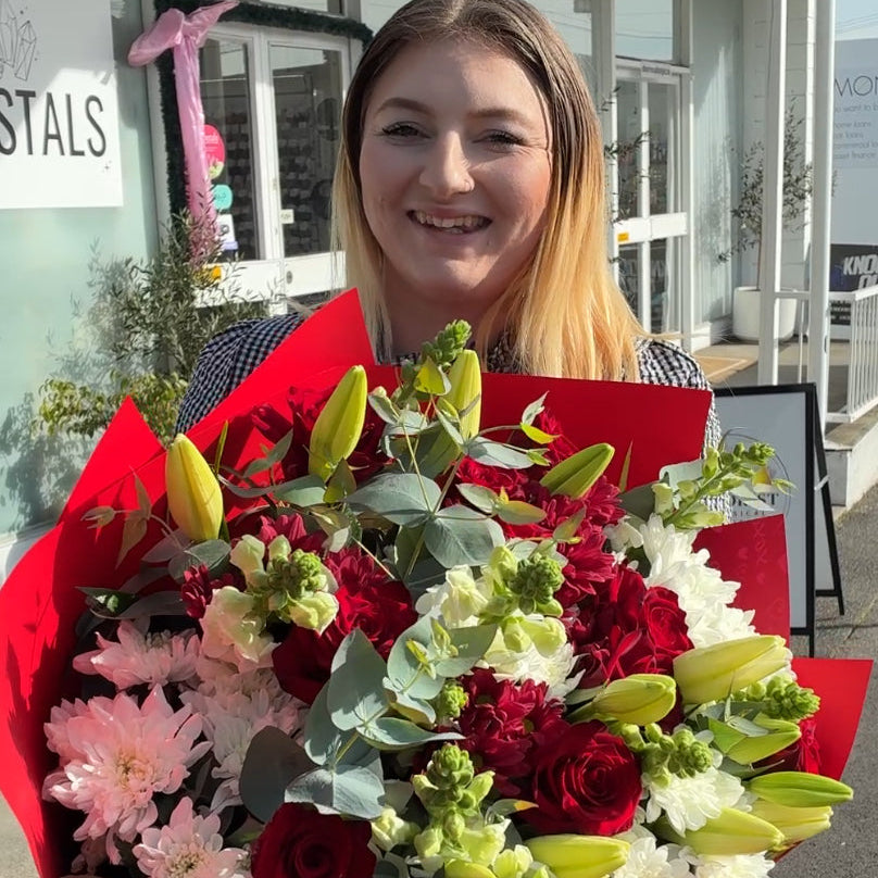 Florist holding a fresh red rose and yellow lily flower bouquet in Launceston.