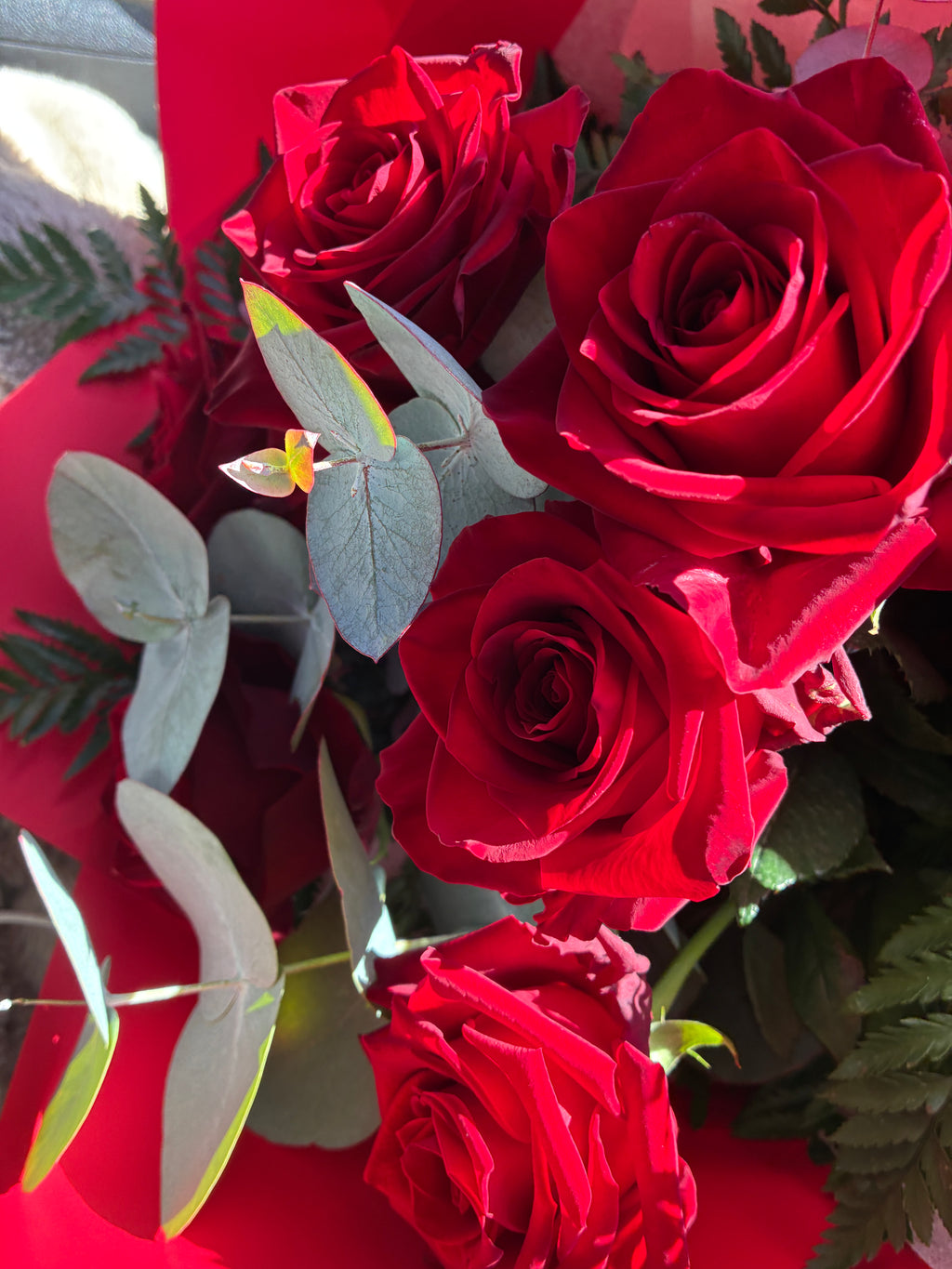 A close-up of a bouquet featuring vibrant red roses and silver eucalyptus available for same day flower delivery in Launceston TAS.