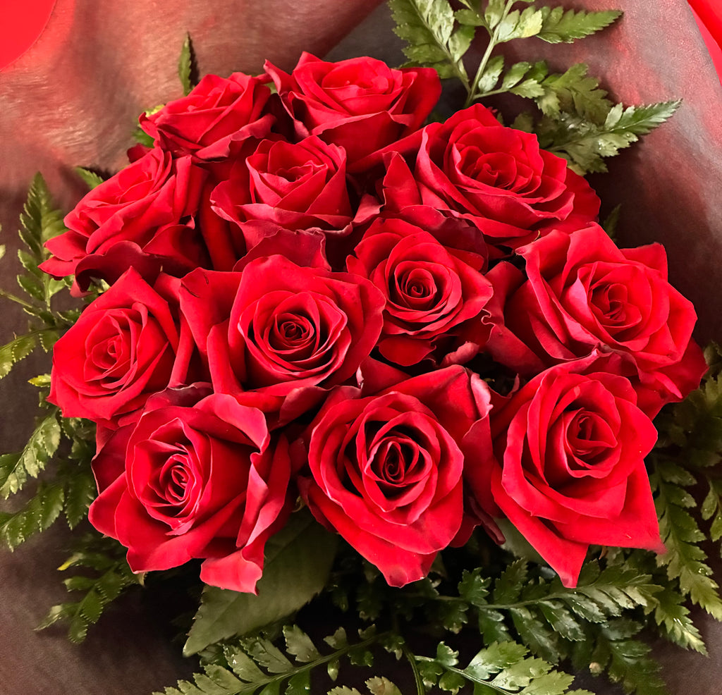 Bouquet of dozen red roses and fern foliage giftwrapped